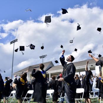 Graduates throwing their caps in the air after a Grad Walk shown